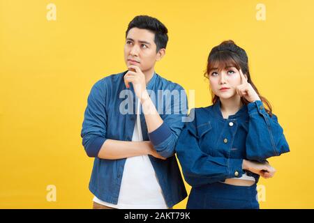Portrait of his he her she nice attractive lovely curious bewildered couple thinking creating solution learning isolated over yellow color backgroun Stock Photo