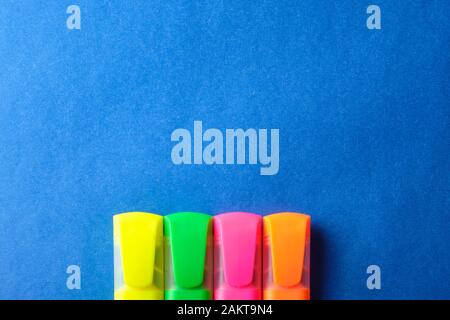 Multi colored highlighters at blue background with copy space. Stock Photo