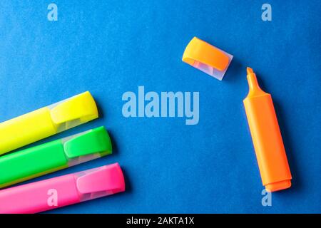 Multi colored highlighters at blue background with copy space. Stock Photo