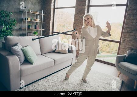 Full length body size view of nice attractive healthy cheery glad cheerful gray-haired grandma dancing with cane having fun retirement at industrial Stock Photo