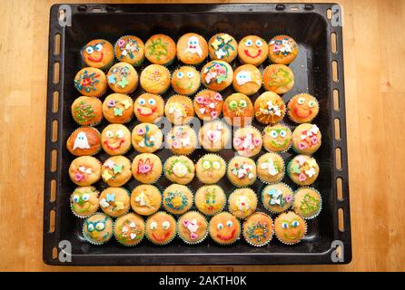 Baking tray full of small homemade muffins with funny decoration ready for a children's birthday party