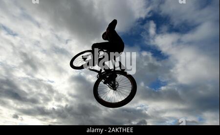 10 January 2020, Hessen, Frankfurt/Main: A teenager jumps with his dirtjump bike on the skater area in the Osthafenpark in front of a cloudy sky. Photo: Arne Dedert/dpa Stock Photo