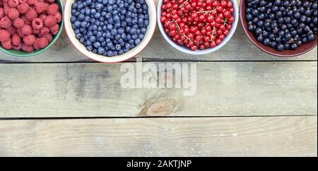 Many bowls with fresh garden and forest berries: raspberry, blueberry, red and black currant, sweet cherries overhead on the wooden table, flat lay, f Stock Photo