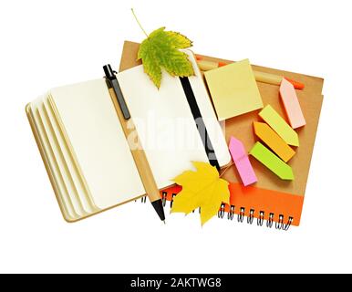 Notebook and pens with dry autumn leaves isolated on white