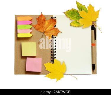 Notebook and pen with dry autumn leaves isolated on white