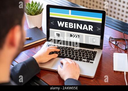 Webinar, online training and education, distance learning concept. Back view of a man working with a computer laptop, webinar text on the screen Stock Photo