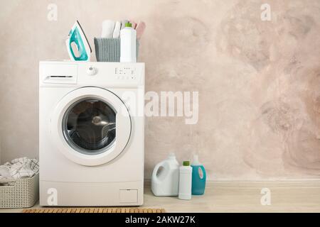 Laundry room with washing machine against light brown wall Stock Photo