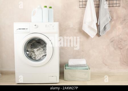 Laundry room with washing machine against light brown wall Stock Photo