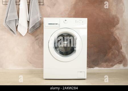 Laundry room with washing machine against brown wall Stock Photo