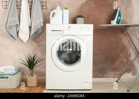 Laundry room with washing machine against brown wall Stock Photo