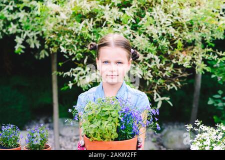 Little girl planting flowers in pots in a home garden Stock Photo