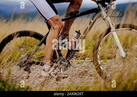 close-up dirty legs cyclist and mountain bike riding trail Stock Photo