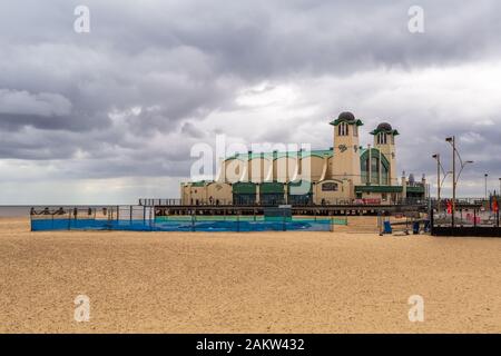 At The Seaside is a photograph taken at Great Yarmouth in Norfolk, UK showing an empty beach and one of the entertainment buildings on a pier. Stock Photo