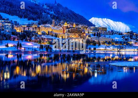 View of beautiful night lights of St. Moritz in Switzerland at night, with reflection from the lake and snow mountains in backgrouind Stock Photo