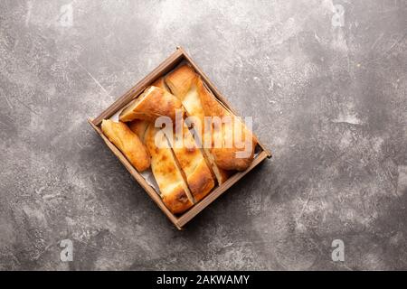 Traditional national Georgian Shoti bread. Sliced bread lies in a wooden box on a gray concrete background. Top view. Stock Photo