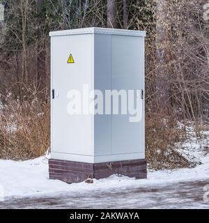 Metal electric cabinet in the forest in the snowdrift. Stock Photo