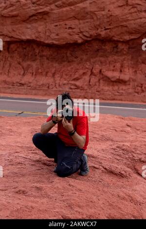 Photographer taking pictures of red earth formations in Quebrada de las Conchas, Salta Region, Argentina Stock Photo