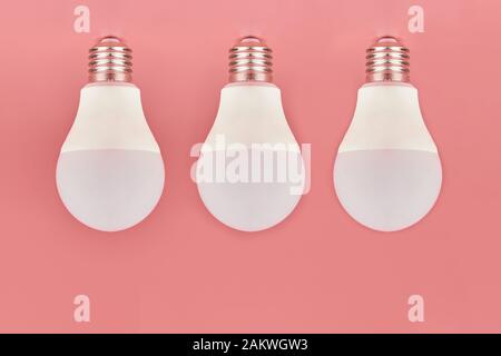 Three light bulbs, copy space. Energy saving minimal idea concept.Pink background. Stock Photo