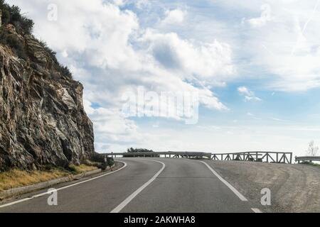 A sharp bend on an empty tarmac road with street signs. Edge of the cliff Stock Photo