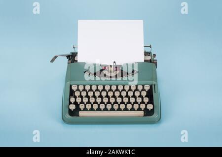 Retro old typewriter with paper on light blue background Stock Photo