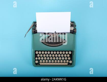 Retro old typewriter with paper on light blue background Stock Photo