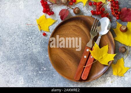 Autumn table setting. Thanksgiving or autumn harvest table setting with rustic silverware and frame of leaves. Top view flat lay. Free space for your Stock Photo