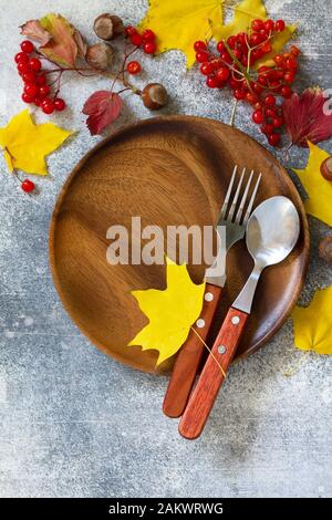 Autumn table setting. Thanksgiving or autumn harvest table setting with rustic silverware and frame of leaves. Top view flat lay. Free space for your Stock Photo
