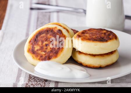 Cottage cheese pancakes, homemade traditional Ukrainian  syrniki served with  sour cream on rustic table, healthy breakfast or brunch Stock Photo