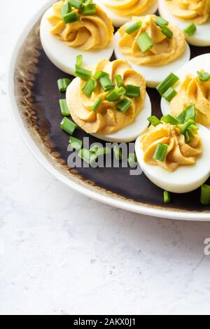 Deviled eggs in rustic ceramic plate, Easter party snack, close up Stock Photo