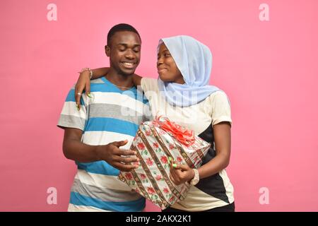 young black man gives his girlfriend a present, she hugs him Stock Photo