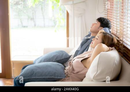 Young asian couple smile relax comfortable on sofa in the living room in holiday, family leisure and resting with happy in vacation on couch at home, Stock Photo