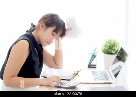 Beautiful young asian woman calculating expenses household and writing notebook on desk, girl checking bill and stress and note, female worry debt and Stock Photo