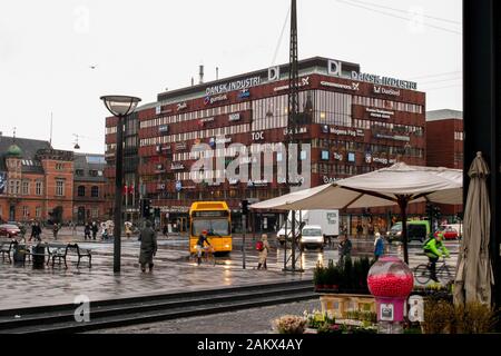 A grey wet winter's day as a yellow bus and cyclists travel along a road in Denmark in front of the Confederation of Danish Industry (DI) building. Stock Photo