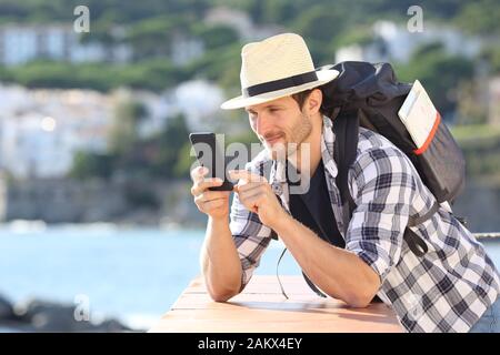 Serious tourist checking mobile phone in a balcony in a coast town on summer vacation Stock Photo