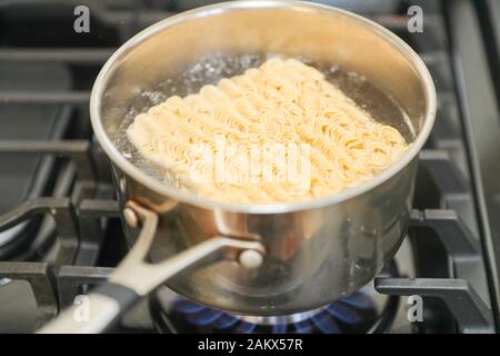 Instant noodle. Boiling water for fast-cooking instant noodle in a pot. Popular Thai style hot and spicy soup noodle in Chinese food noodles. High sod Stock Photo