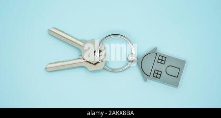 key chain with house symbol and keys on blue background,Real estate concept Stock Photo