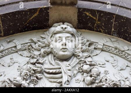 A close up view of a stone carving of a mans head above a doorway Stock Photo