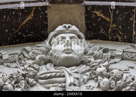 A close up view of a stone carving of a mans head above a doorway Stock Photo