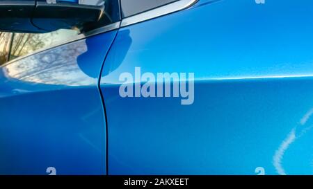 A small dent in the fender of a blue metallic European car Stock Photo