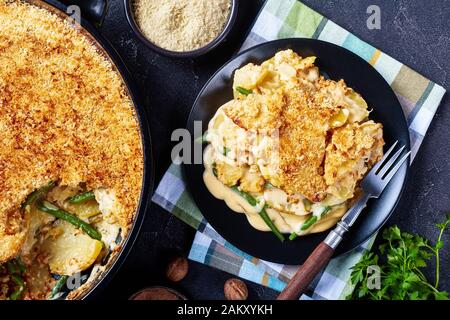 a portion of cheesy Potato and green bean casserole with crunchy breadcrumbs topping served on a plate, horizontal view from above, close-up Stock Photo