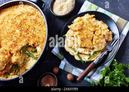 close-up of a portion of cheesy Potato and green bean casserole with crunchy breadcrumbs topping served on a plate, horizontal view from above Stock Photo