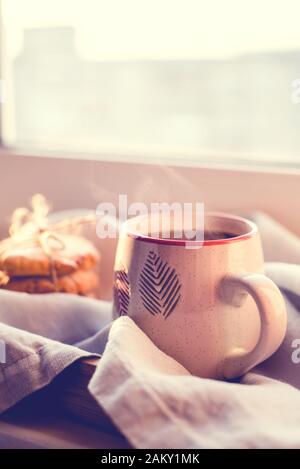 A steaming cup of tea or coffee with cookies by the window. Stock Photo