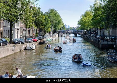 In summertime people having fun with theirs boats in the canals of Amsterdam, Netherlands. Stock Photo