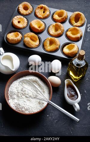 freshly baked Yorkshire puddings in baking tray on a concrete table with ingredients, english cuisine, vertical view from above Stock Photo