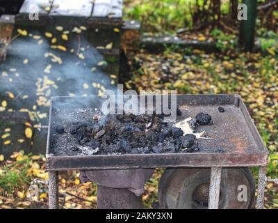 Blacksmith portable furnace with burning coals, tools for hot metal forging workpieces Stock Photo