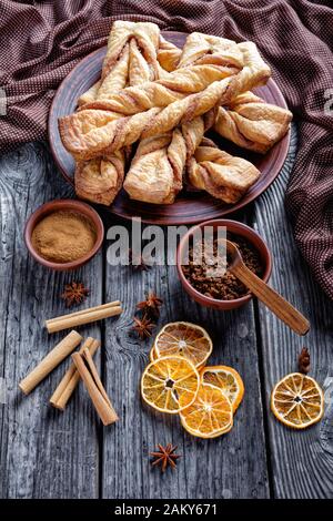 freshly baked Cinnamon sugar puff pastry twists on a plate on a wooden rustic table, vertical view from above Stock Photo
