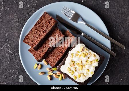Dark Molasses Gingerbread Cake with fresh whipped cream on top and finely chopped pistachios, horizontal view from above, flatlay Stock Photo