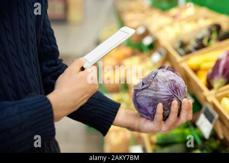 Young adult man in supermarket using modern smartphone Stock Photo