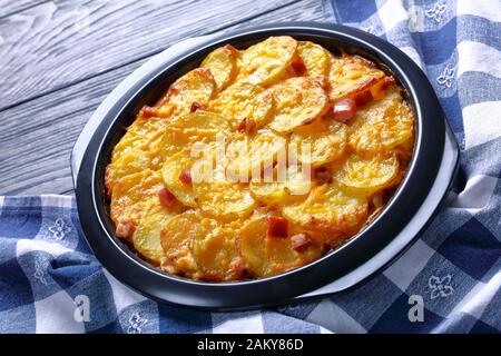 Old fashioned scalloped potatoes and ham with melted cheese in a baking dish, close-up Stock Photo