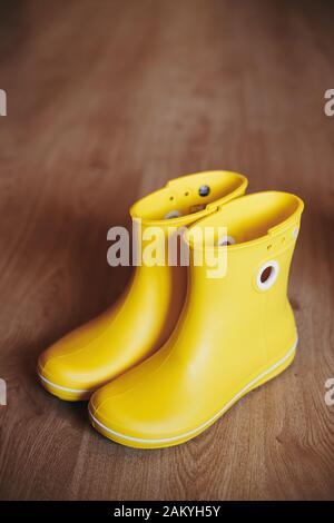 Yellow rubber boots isolated on wooden background. Stock Photo